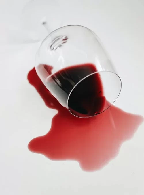 A wine glass that spilled its contents on the floor.